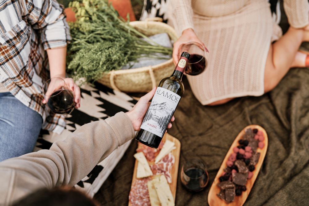 Alamos Malbec being shared by friends with food.